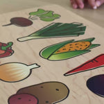 Little girl with a wooden cutting board and knife with veggies printed on it.