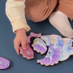 Little kids sitting on the floor constructing wooden magnetic dinosaur puzzles.