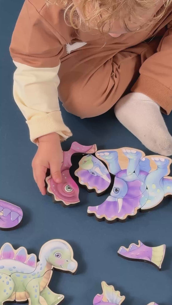 Little kids sitting on the floor constructing wooden magnetic dinosaur puzzles.