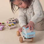A girl concentrating on putting together a Montessori inspired stackable ice cream truck with colorful shapes.