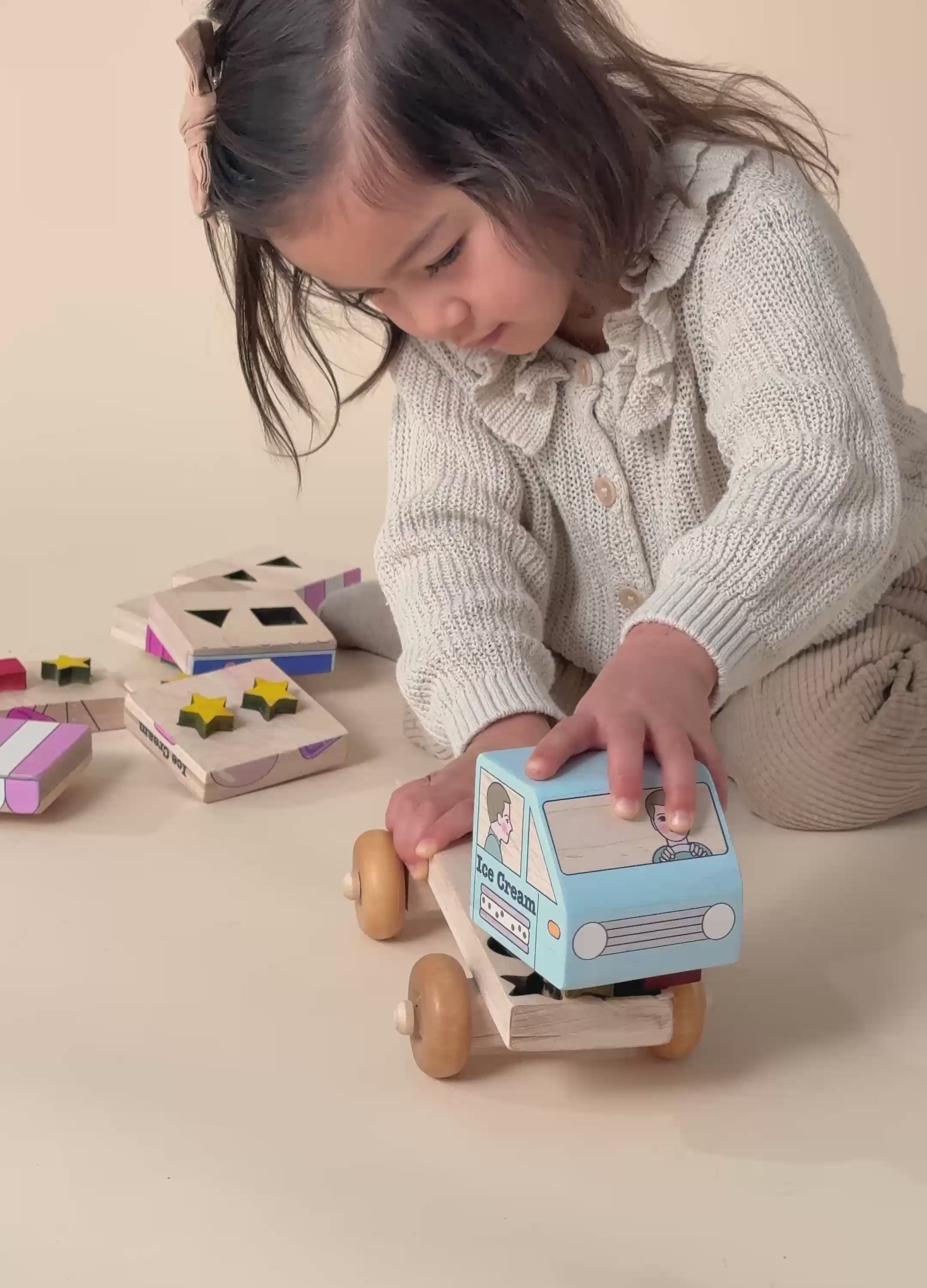 A girl concentrating on putting together a Montessori inspired stackable ice cream truck with colorful shapes.
