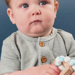 An adorable baby with a wooden and silicone heart teether. 